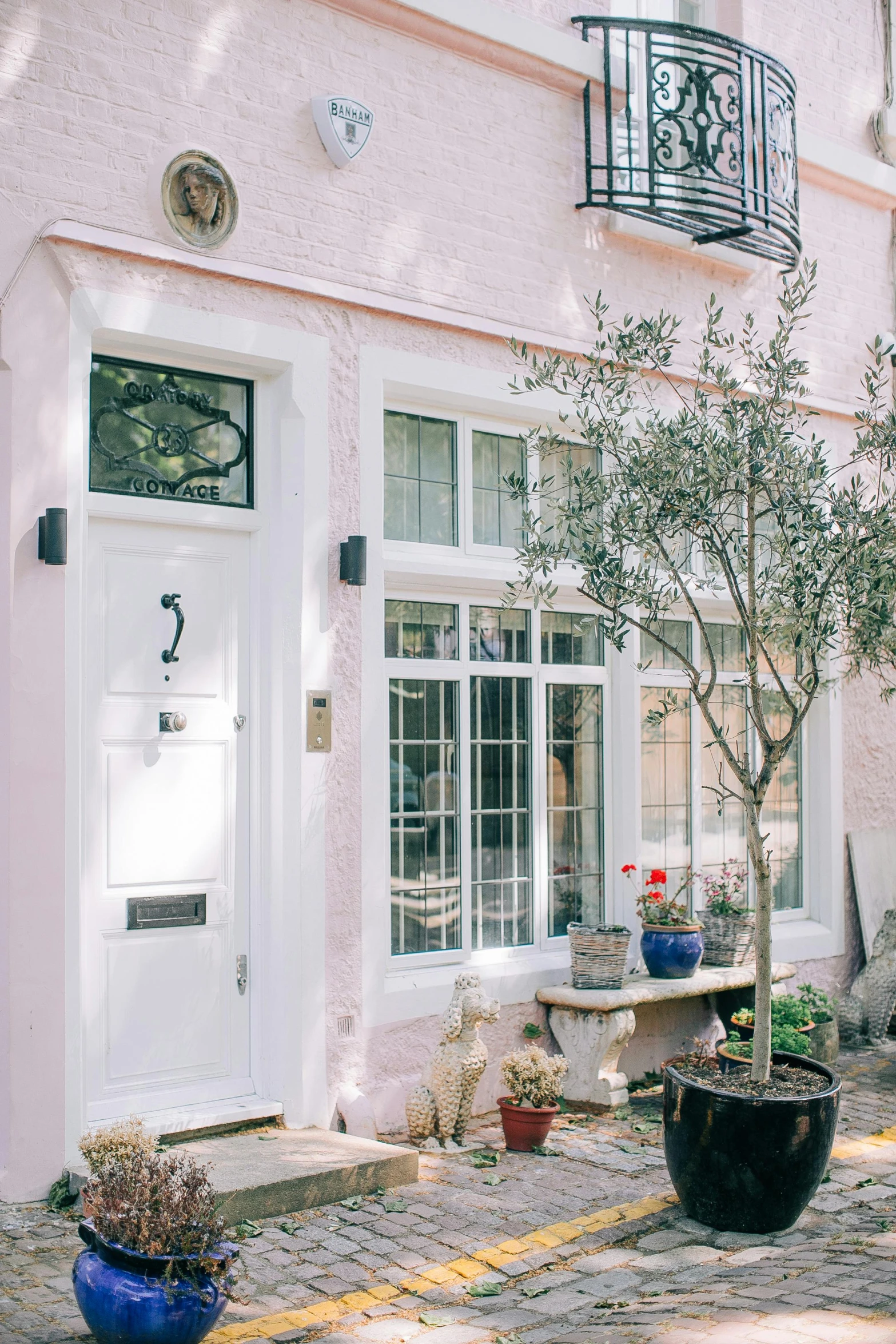 a white door sitting on the side of a pink building, inspired by Albert Paris Gütersloh, pexels contest winner, olive trees, bay window, architectural digest, in london