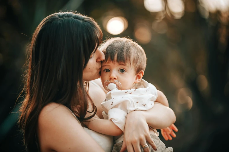 a woman holding a baby in her arms, pexels contest winner, avatar image, brunette, thumbnail, tiny mouth