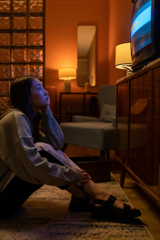 a woman sitting on the floor in front of a tv, trending on reddit, emotional lighting, hotel room, atmospheric cool colorgrade, concerned