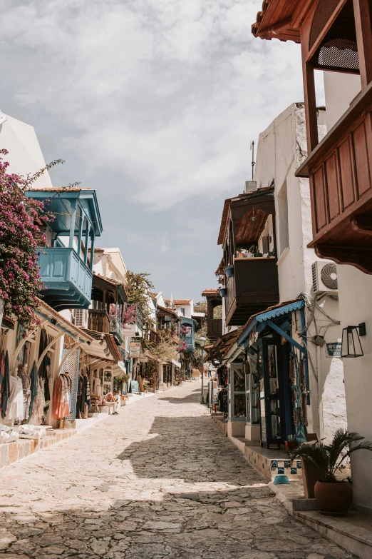 a narrow cobblestone street lined with shops, pexels contest winner, summer street near a beach, turkey, cottagecore hippie, preserved historical