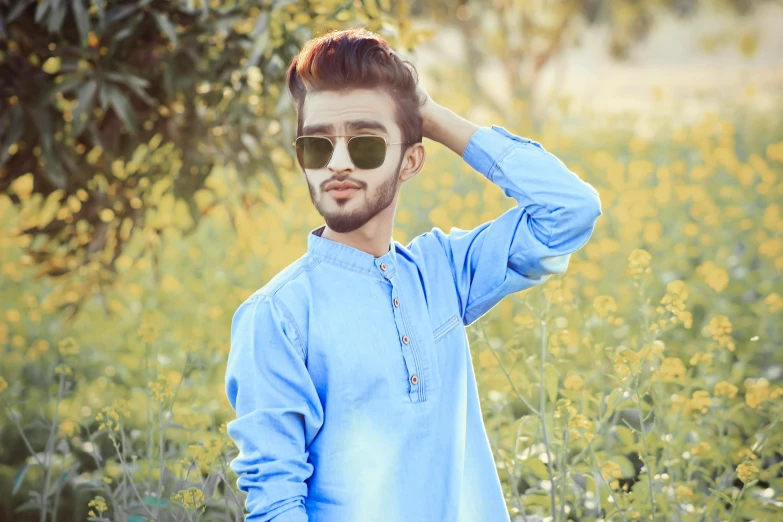 a man standing in a field of yellow flowers, inspired by Saurabh Jethani, trending on pixabay, realism, wearing blue sunglasses, avatar image, wearing a kurta, handsome young man