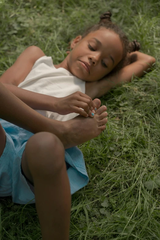 a little girl laying on top of a lush green field, an album cover, by Elsa Bleda, pexels contest winner, painted nails, african american, resting after a hard fight, feet and hands