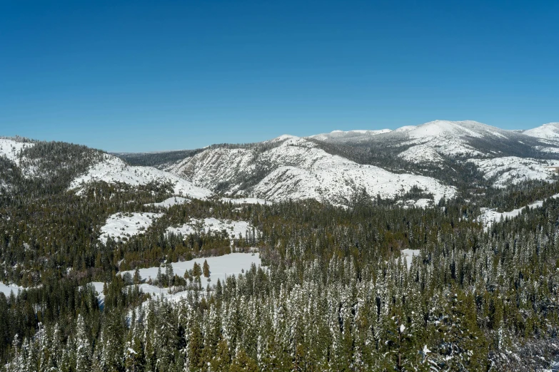 a man riding skis on top of a snow covered slope, a photo, evergreen valley, obsidian towers in the distance, ultrawide image, trees in foreground