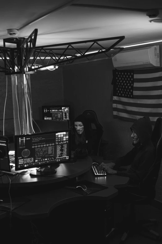 a man sitting at a desk in front of a computer, a black and white photo, by Bascove, reddit, realism, crystal castles, sitting at a control center, patriotism, live performance