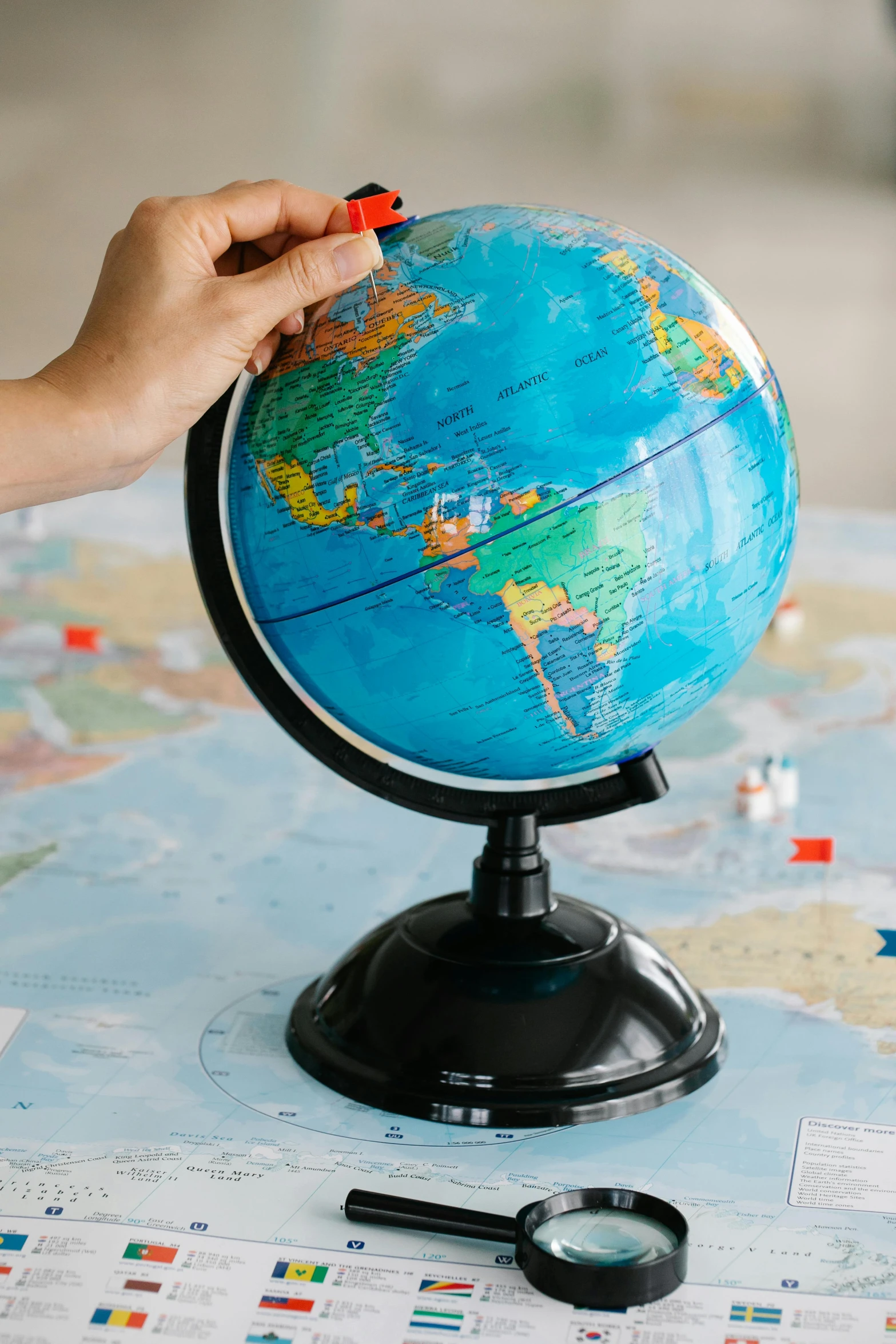 a person holding a magnifying glass in front of a globe, a jigsaw puzzle, educational display case, thumbnail, tabletop, navy