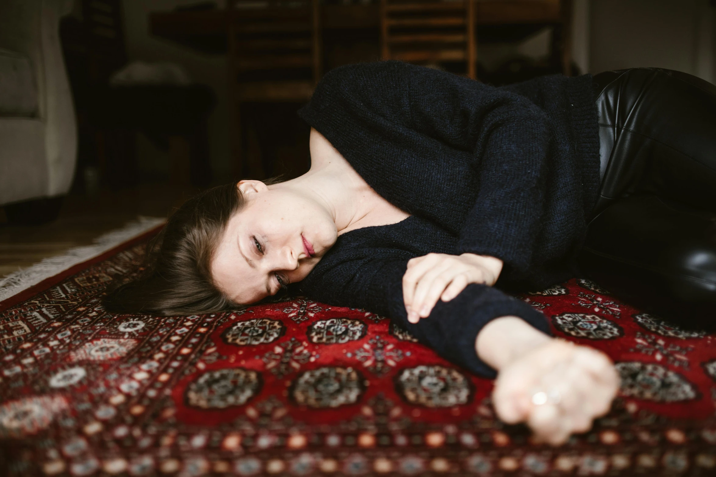 a woman laying on a rug on the floor, by Julia Pishtar, trending on pexels, hurufiyya, despondent, on a velvet tablecloth, black wool sweater, kai carpenter