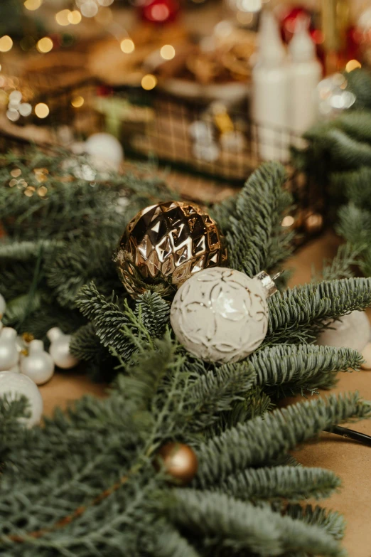 a close up of christmas decorations on a table, evergreen branches, intricate white and gold neon, globes, zoomed in