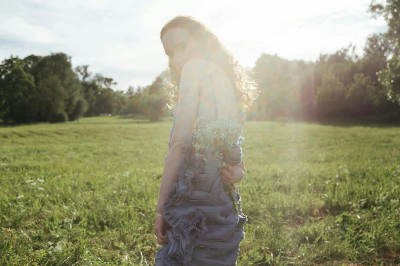 a woman standing on top of a lush green field, inspired by Elsa Bleda, renaissance, soft grey and blue natural light, francesca woodman style, with the sun shining on it, at a fashion shoot