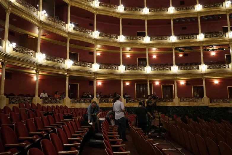 a large auditorium with red seats and chandeliers, by Gina Pellón, instagram, art nouveau, 3 actors on stage, guanajuato, very sad, thumbnail