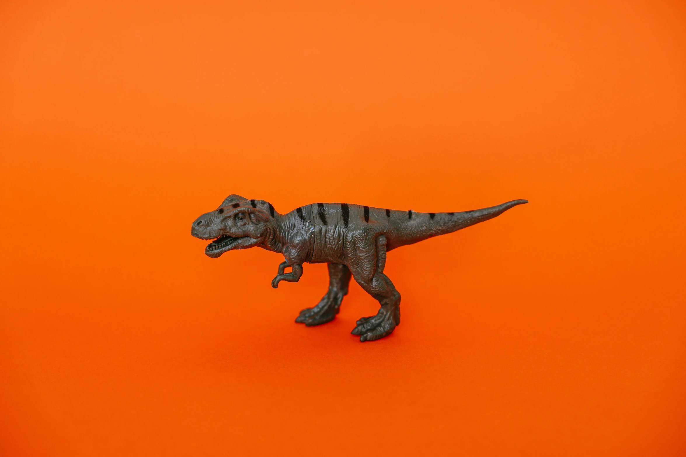 a toy t - rex on an orange background, inspired by Adam Rex, pexels contest winner, photorealism, grey, made of bronze, miniature product photo, 🦩🪐🐞👩🏻🦳