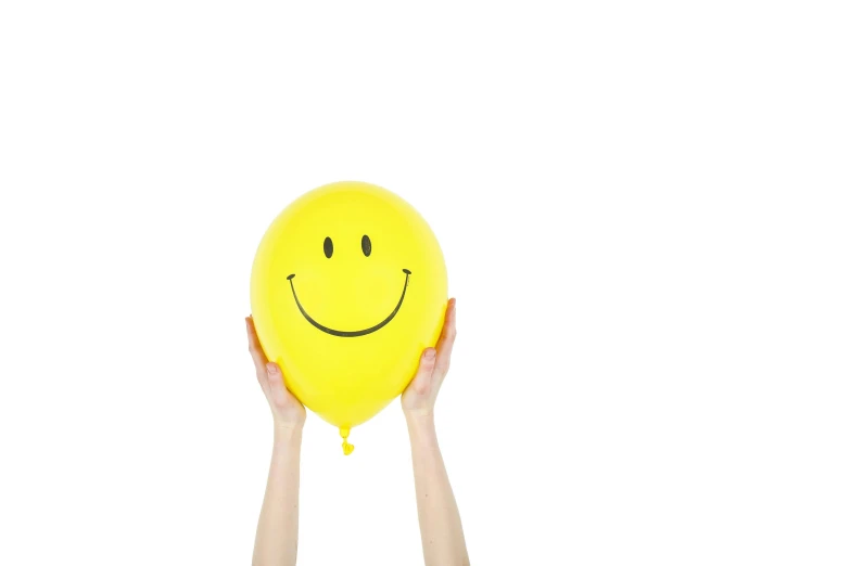 a person holding a yellow balloon with a smiley face on it, with a white background, item, balloon, backdrop