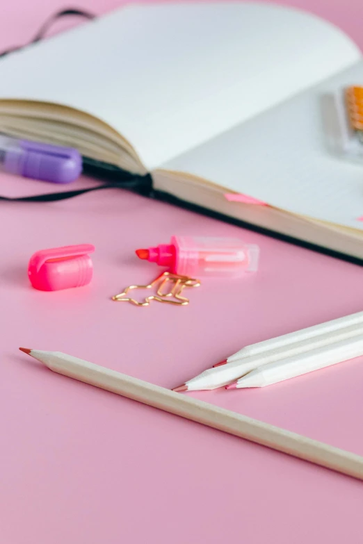 an open book sitting on top of a pink table, pencils, detailed product image, fluorescent colors, multiple stories