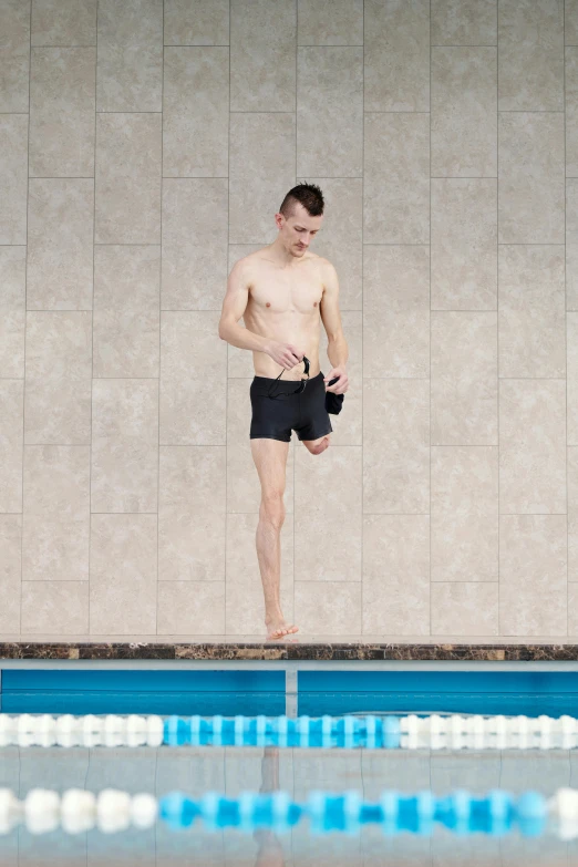 a man standing on the edge of a swimming pool, by Jacob Toorenvliet, perfect dynamic posture, wearing black shorts, terrified, mechanics