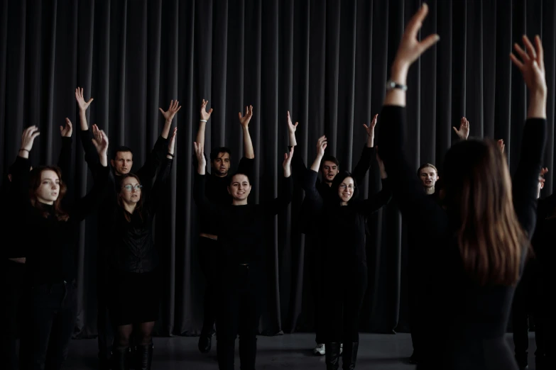 a group of people standing in front of a curtain, unsplash, antipodeans, polovstian dances and chorus, wearing black clothes, hands reaching for her, animation