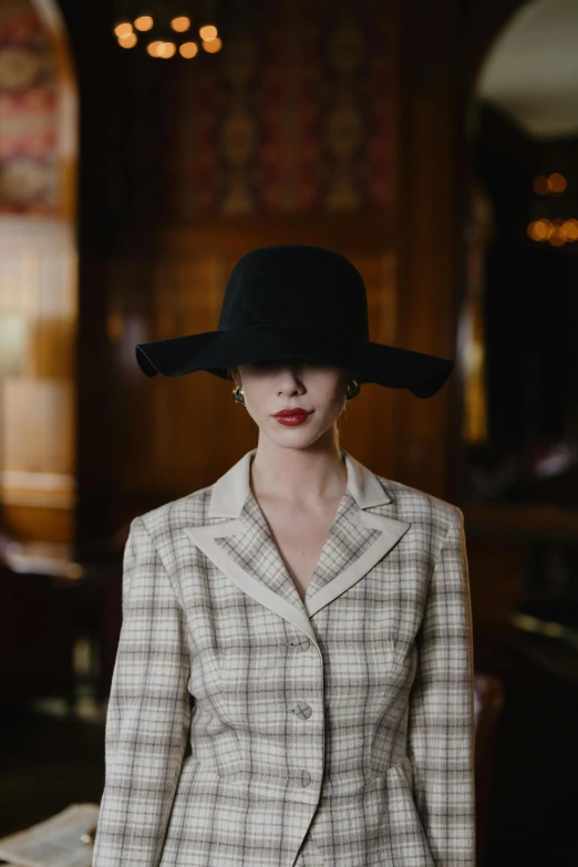 a woman standing in a room with a hat on her head, inspired by Peter Lindbergh, unsplash, old wool suit, chanel, square, high society