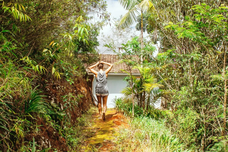 a woman standing in the middle of a forest, sri lanka, small path up to door, tropical vibe, on a bright day