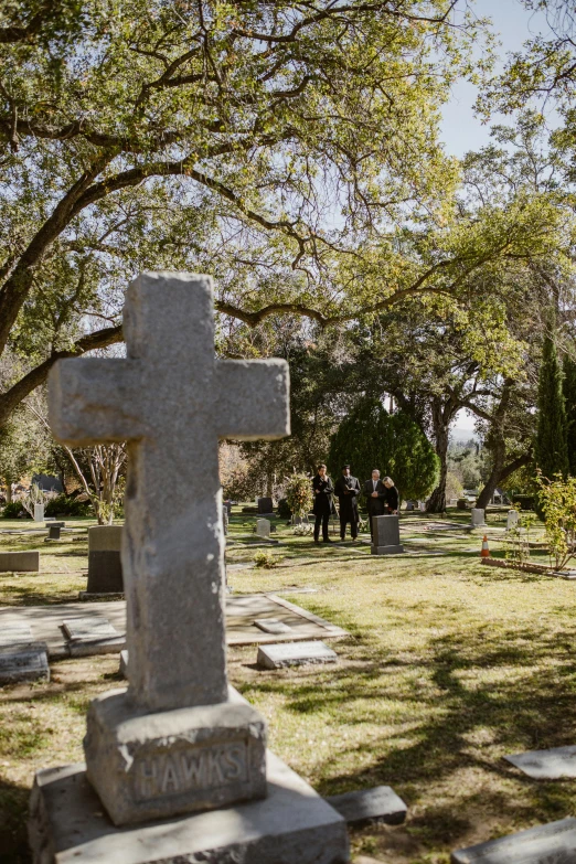 a cemetery with a cross in the middle of it, actors, over the shoulder view, lush surroundings, daytime