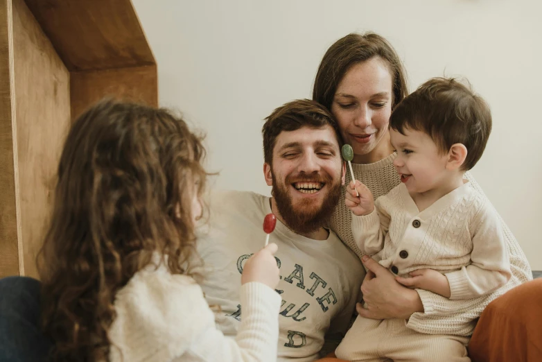 a group of people sitting on top of a couch, by Emma Andijewska, pexels contest winner, caring fatherly wide forehead, holding a yellow toothbrush, families playing, small beard