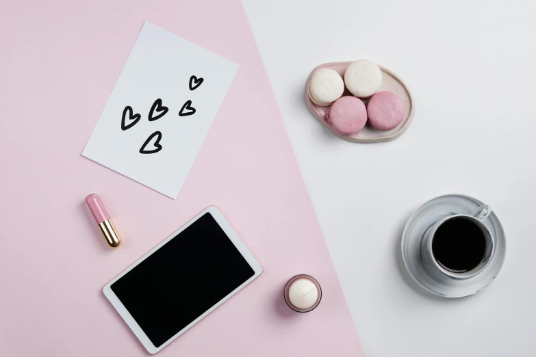 a tablet computer sitting on top of a table next to a cup of coffee, a picture, inspired by Emma Ríos, trending on pexels, aestheticism, pink hearts in the background, candy treatments, black white pastel pink, photoshoot for skincare brand