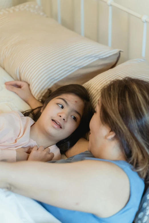 a woman laying on top of a bed next to a little girl, pexels contest winner, incoherents, looking at each other mindlessly, cindy avelino, high angle close up shot, multiple stories