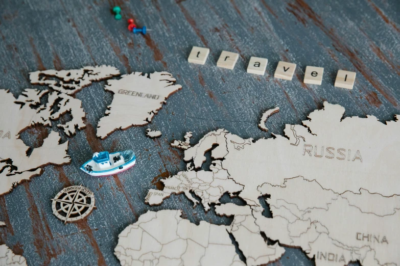 a toy boat sitting on top of a map of the world, a jigsaw puzzle, graffiti, bespoke, grey, birch, board games