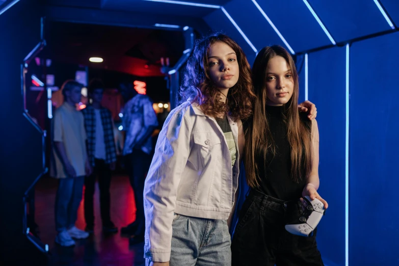 a couple of women standing next to each other, by Adam Marczyński, pexels, sci-fi night club, dafne keen, kids, posing for a picture