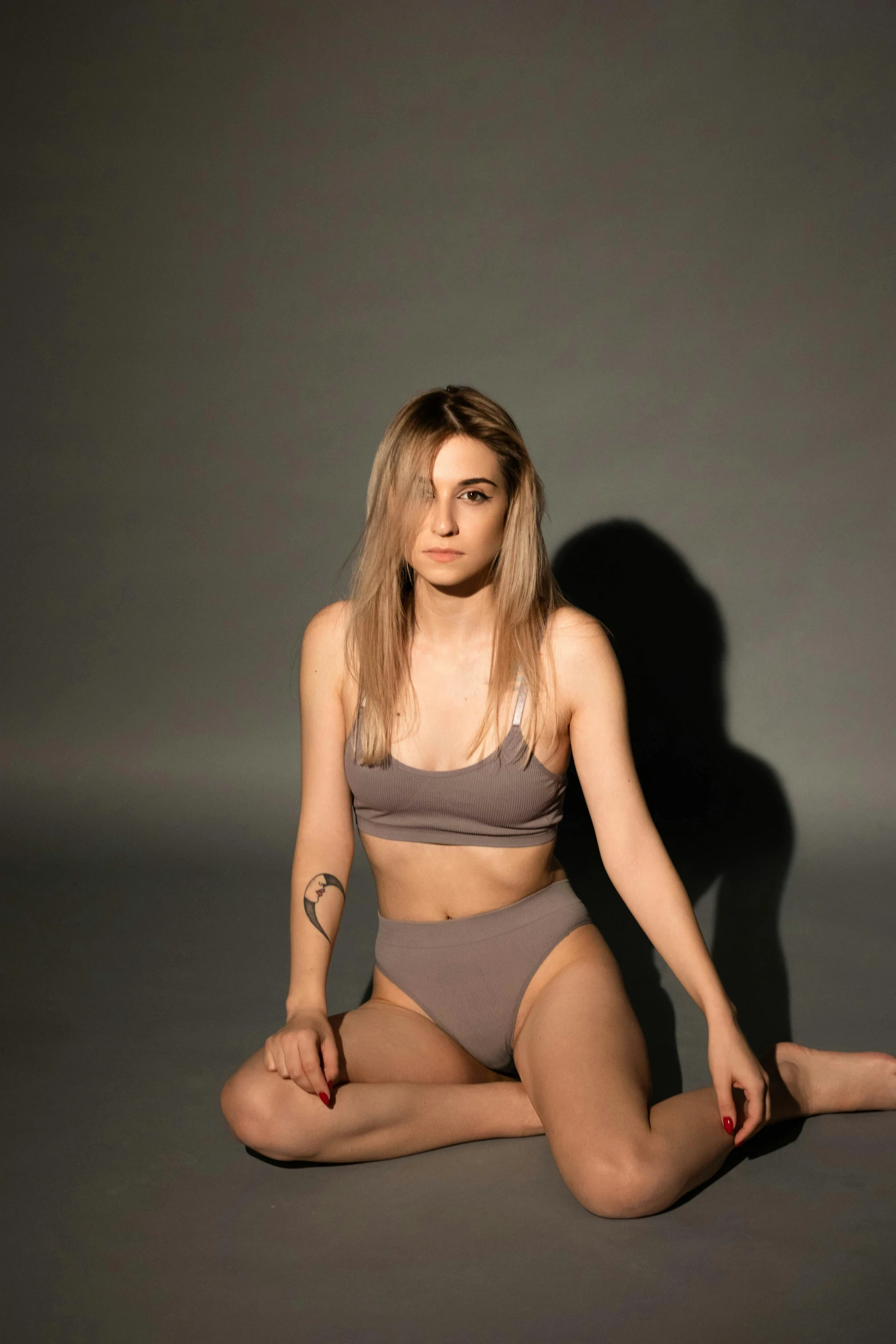 a woman in a bikini sitting on the floor, an album cover, inspired by Elsa Bleda, trending on pexels, photorealism, standing pose, grey, cinematic outfit photo, wearing a crop top