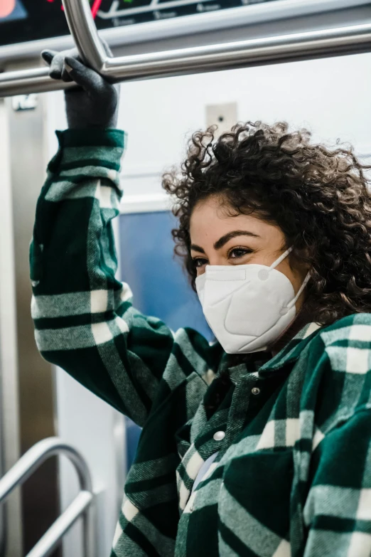 a woman wearing a face mask while riding a subway, trending on pexels, renaissance, curly haired, wearing a hospital gown, lorde, smog