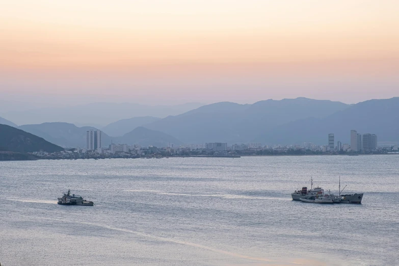 a couple of boats that are in the water, pexels contest winner, sōsaku hanga, city in the distance, shot on 1 5 0 mm, ehime, sunset panorama