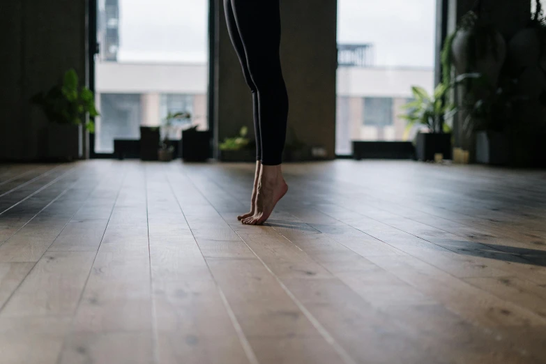 a woman standing on a hard wood floor, unsplash, arabesque, background image, bare leg, person in foreground, balance