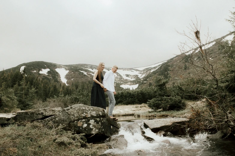 a man and woman standing on a rock next to a river, by Emma Andijewska, pexels contest winner, 2 5 6 x 2 5 6 pixels, on the mountain, standing elegantly, on a canva