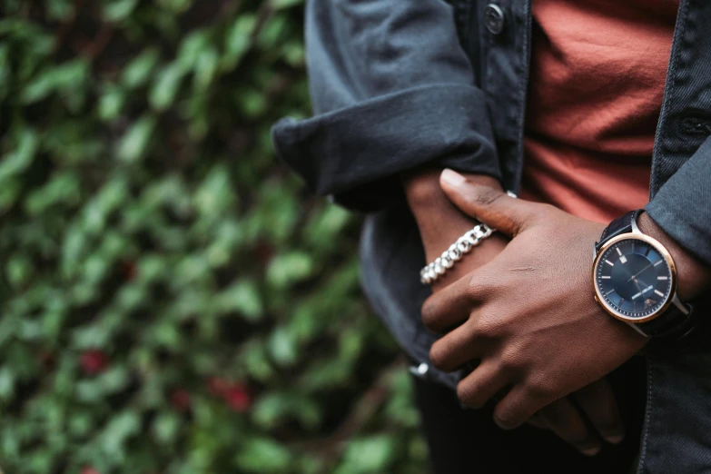 a close up of a person wearing a watch, an album cover, inspired by L. A. Ring, trending on pexels, black teenage boy, wearing two silver bracelets, wearing jacket, 15081959 21121991 01012000 4k