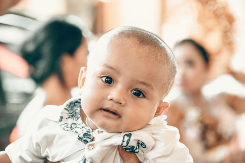 a close up of a person holding a baby, pexels contest winner, hurufiyya, barong family, looking straight to camera, baptism, serious focussed look