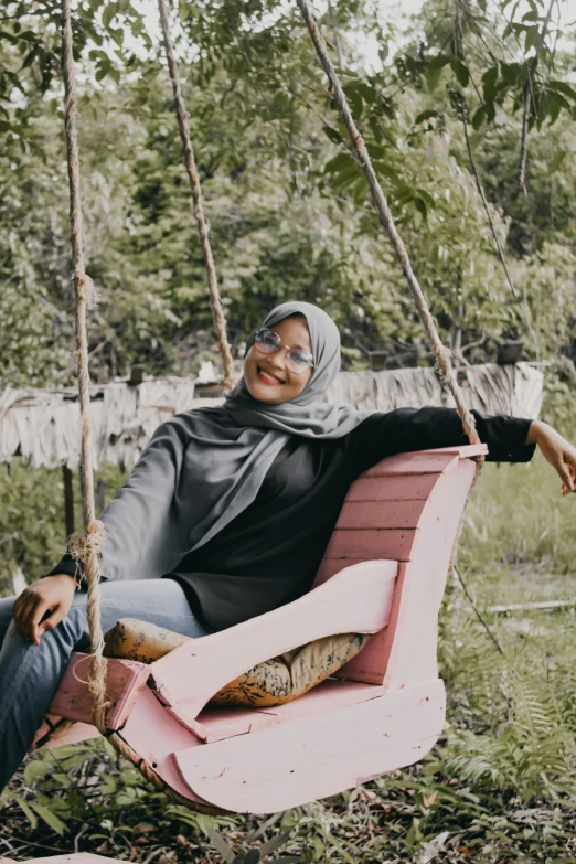 a man and a woman sitting on a swing, a picture, inspired by Nazmi Ziya Güran, pexels contest winner, hurufiyya, with grey skin, woman with rose tinted glasses, seated on wooden chair, hijab