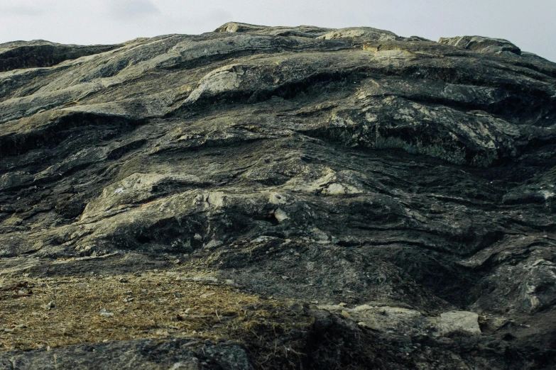 a man standing on top of a rocky hill, an album cover, by Roar Kjernstad, unsplash, hurufiyya, detailed textures, structural geology, palladium veins, anthracite