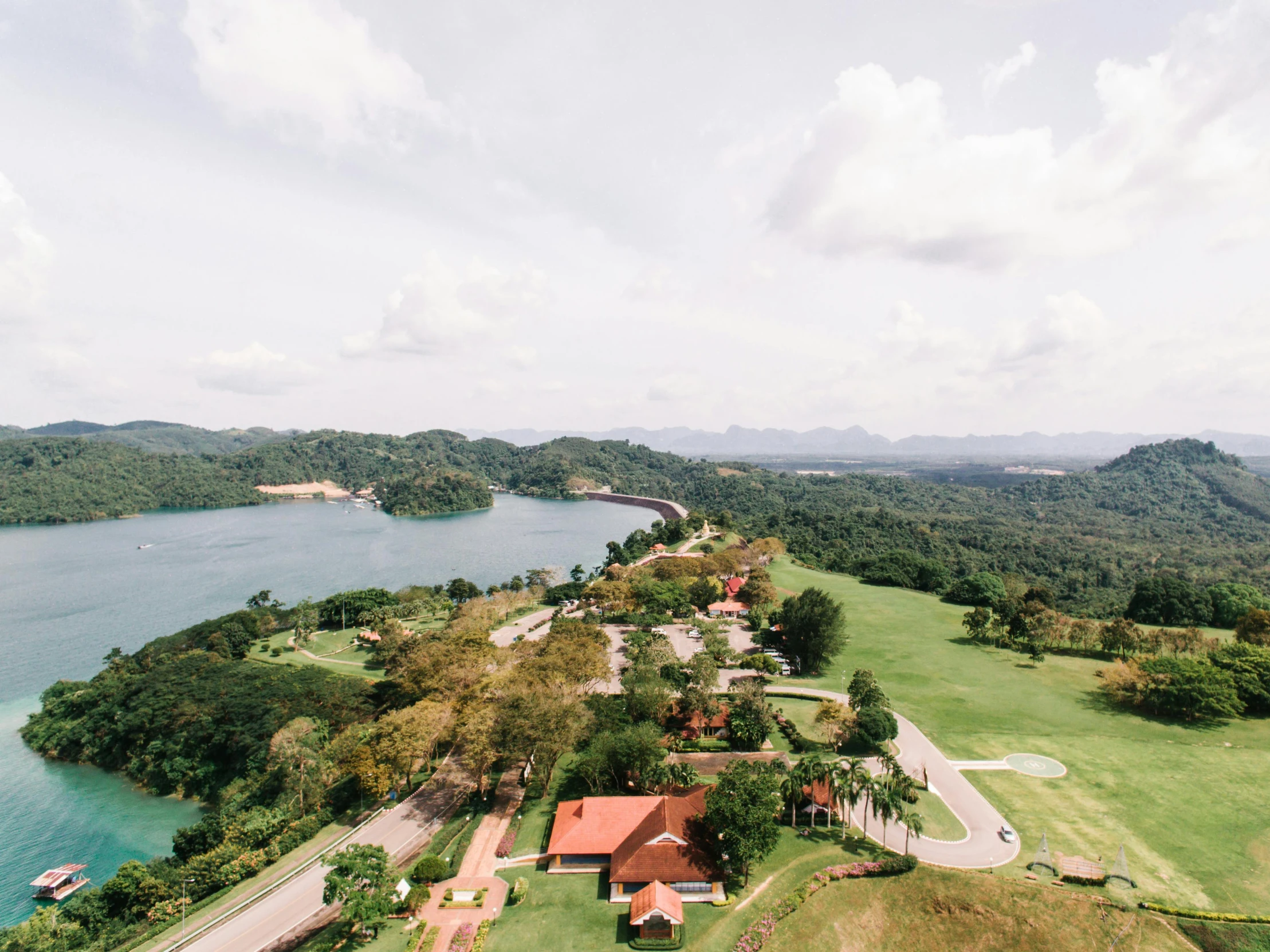 a large body of water next to a lush green hillside, an album cover, pexels contest winner, hurufiyya, alvaro siza, sri lanka, golf course in background, parks and lakes