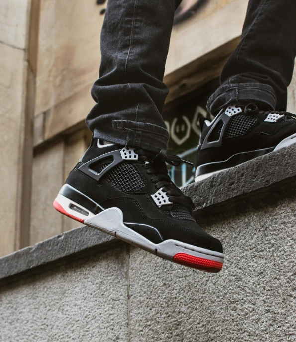 a person standing on a ledge on a skateboard, an album cover, inspired by Jordan Grimmer, unsplash, focus on sneakers only, black and red scheme, high detail 4 k, mkbhd