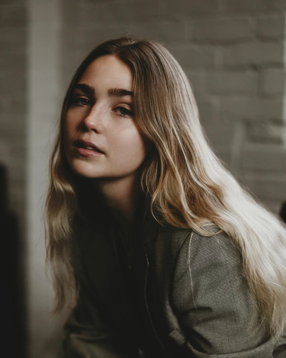 a woman with long blonde hair sitting on a couch, a character portrait, trending on unsplash, modernism, portrait sophie mudd, lilly collins, ash blond greyish hair, on a white table