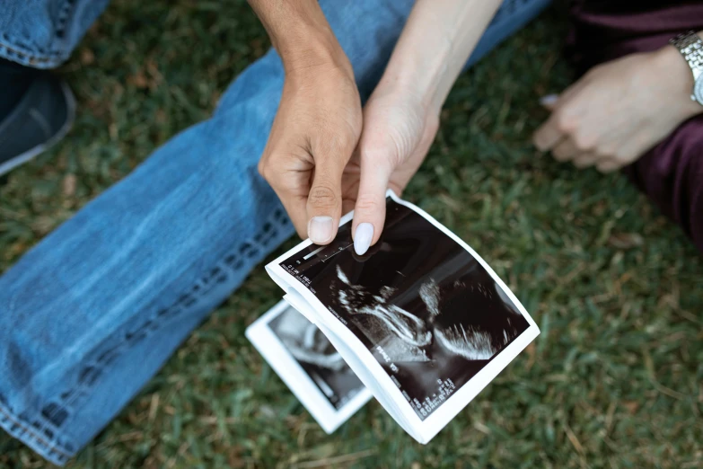 a couple of people sitting on top of a grass covered field, a polaroid photo, by Julia Pishtar, pexels contest winner, happening, fetus, x-ray photography, high angle close up shot, holding close