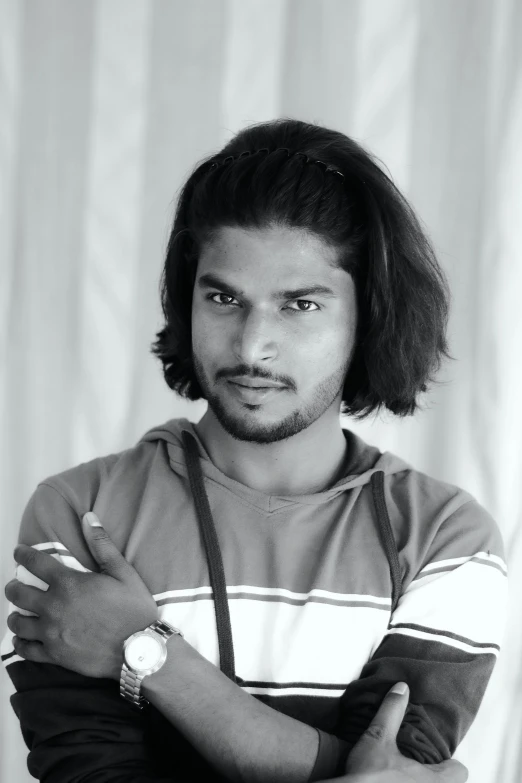 a black and white photo of a man with his arms crossed, a black and white photo, trending on reddit, hurufiyya, mid - length hair, roshan, art student, headshot