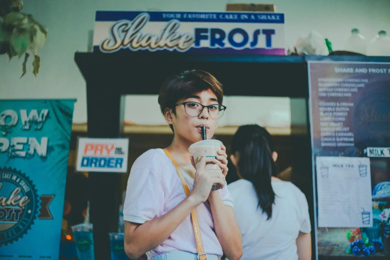 a woman standing in front of a store holding a drink, pexels contest winner, milkshake, frozen cold stare, avatar image, asian male