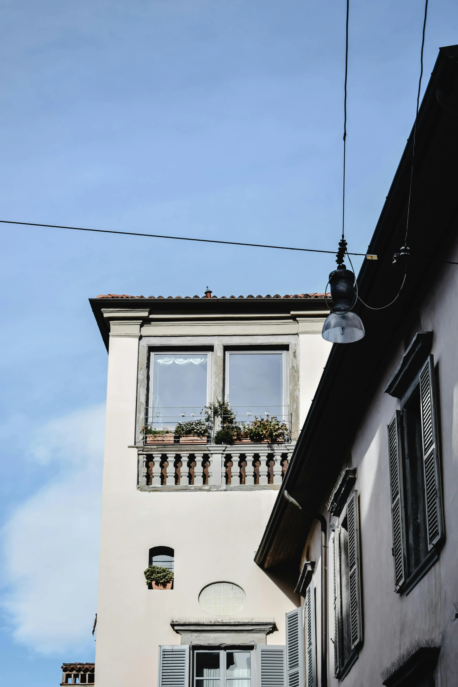 a couple of buildings that are next to each other, inspired by Michelangelo Buonarotti, wires hanging across windows, window with flower box, shot from roofline, clear blue skies