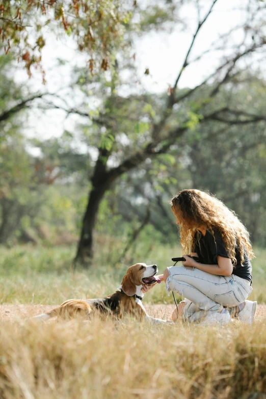a woman kneeling in a field with two dogs, pexels, checking her cell phone, talking, realistic »