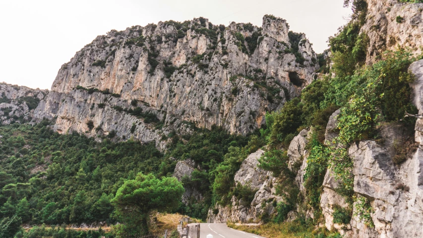 a motorcycle is parked on the side of the road, by Raphaël Collin, pexels contest winner, les nabis, detailed trees and cliffs, limestone, 2000s photo, panoramic