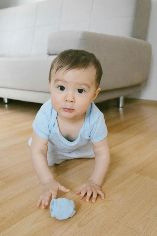a baby crawling on the floor in a living room, pexels contest winner, happening, wearing a light blue shirt, very handsome, smooth feature, small upturned nose