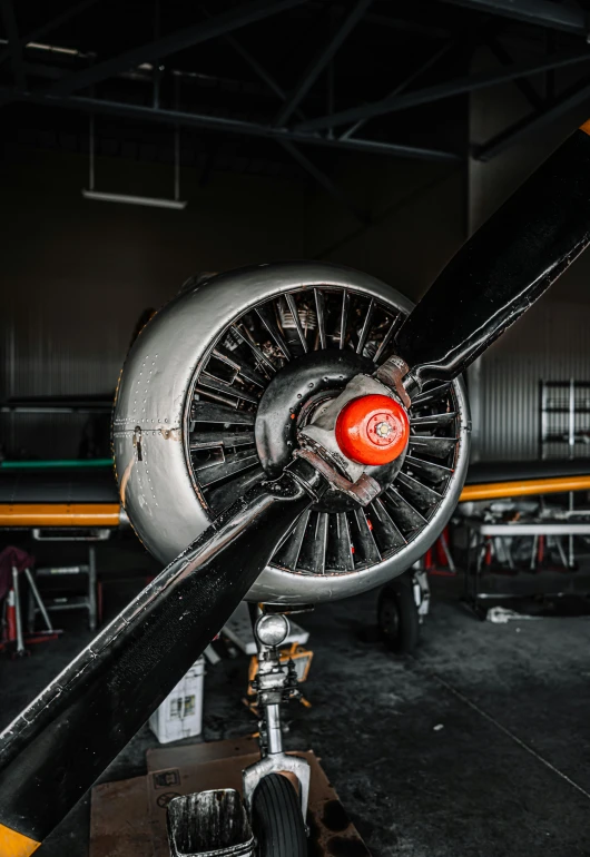 a close up of a propeller on a plane, a colorized photo, pexels contest winner, inside futuristic hangar, featuring engine, profile image, black steel with red trim