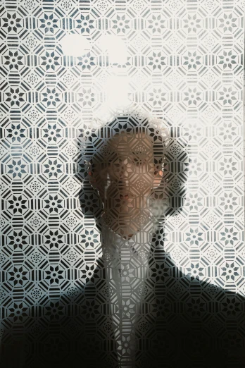 a man in a suit and tie standing in front of a wall, an album cover, inspired by Anna Füssli, unsplash, generative art, patterned tilework, looking through frosted glass, faces covered in shadows, zack de la rocha