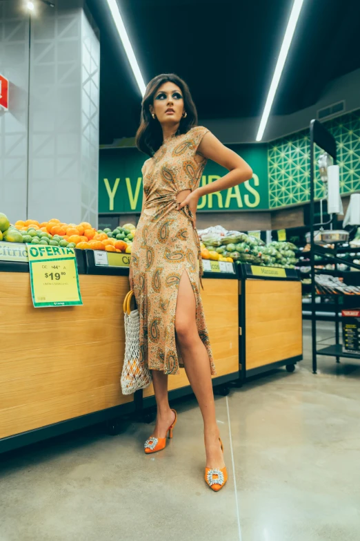 a woman standing in front of a fruit stand, a picture, by Julia Pishtar, trending on pexels, renaissance, low cut dress, inside a supermarket, heels, patterned clothing