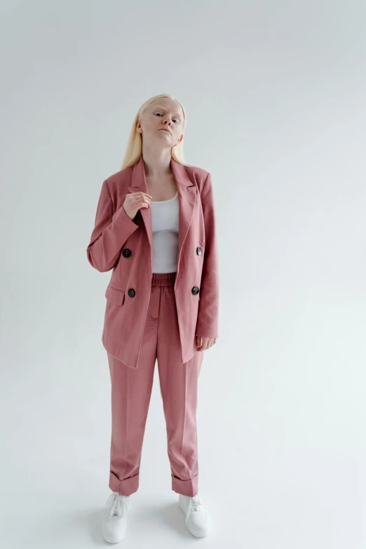 a woman in a pink suit and white sneakers, inspired by Maud Naftel, trending on pexels, muted colors. ue 5, velvet blazer, met collection, on grey background