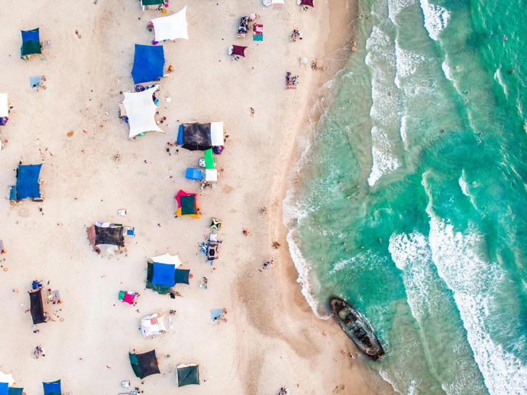 a group of people laying on top of a sandy beach, by Daniel Lieske, pexels contest winner, huts, helicopter view, photo of the middle of the ocean, slightly pixelated